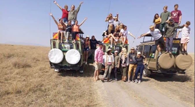 Happy tousist standing on top of the super 4x4 inside queen Elizabeth national park