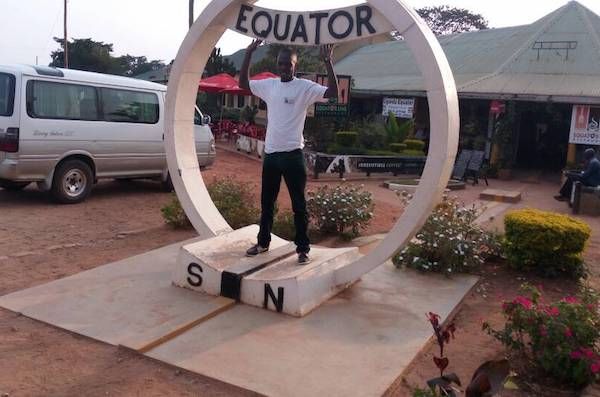 A tourist posing for a photo at Equator monument in Uganda