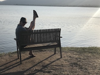 A happy tourist posit with legs up in the sky at the shores of Lake Mburo